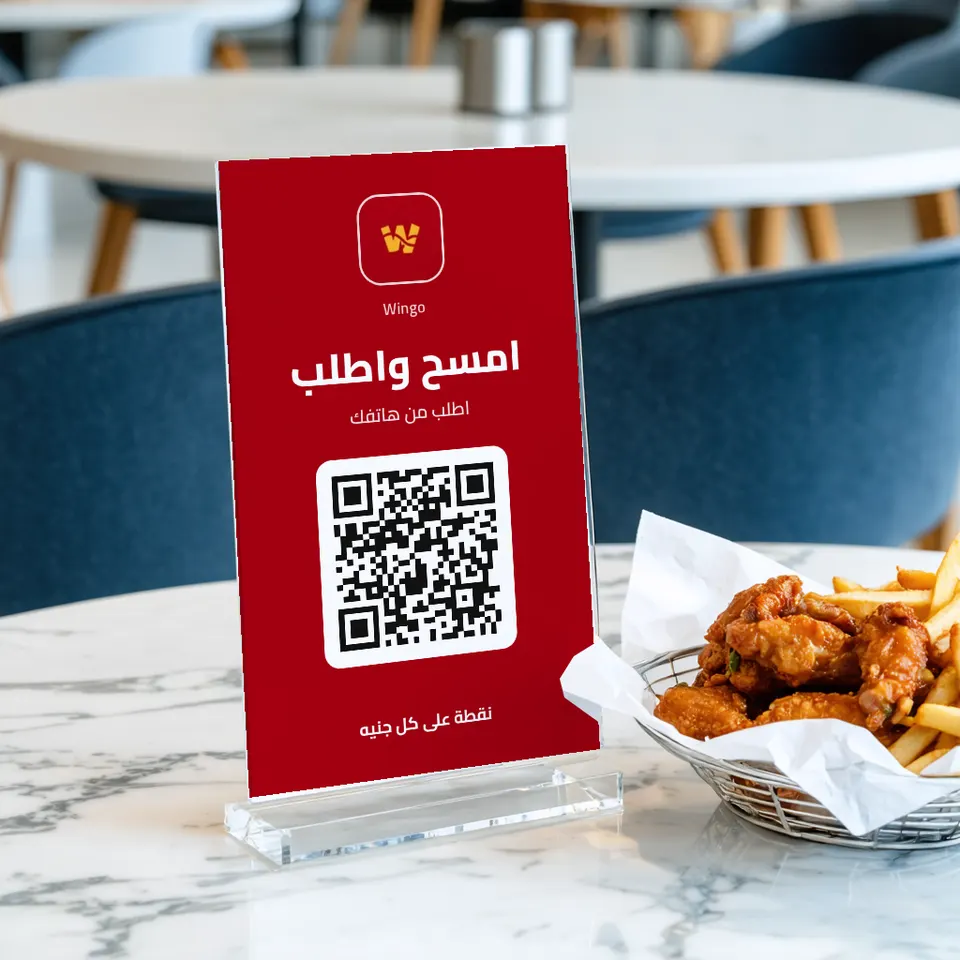 لوحة «امسح واطلب» لمطعم Wingo على طاولة بجانب أجنحة دجاج