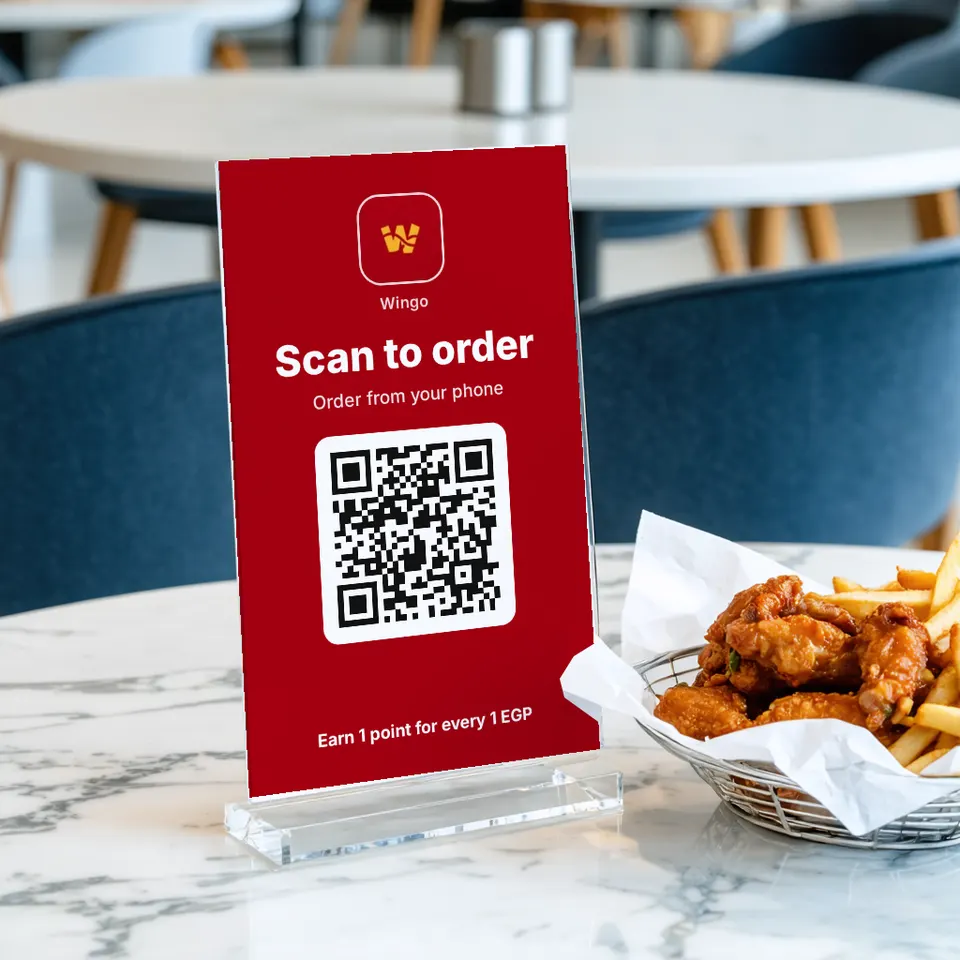 A "Scan to order" sign for Wingo on a restaurant table next to chicken wings